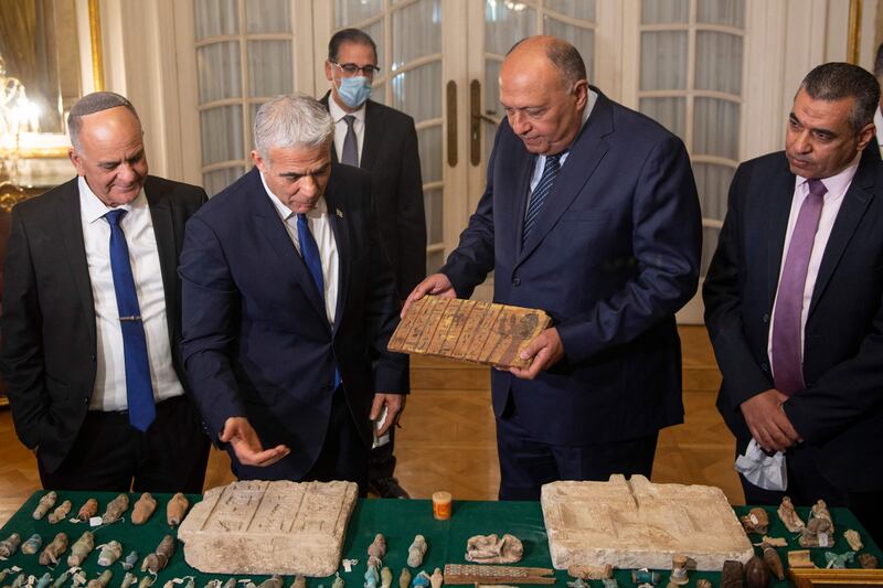 Israel Antiquities Authority Director Eli Escozido, left, looks on as Mr Lapid, centre left, presents Mr Shoukry with the stolen Egyptian artefacts. AFP