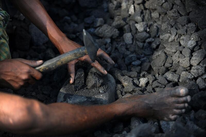 A miner breaks up pieces of coal at a depot in Siliguri. A report in 2012 alleged that India lost out on more than US$33 billion because coal mining permits were awarded to companies without an auction process. Diptendu Dutta / AFP