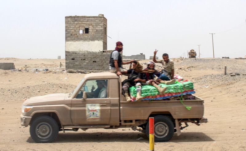 Yemeni fighters from the Amalqa ("Giants") Brigades, loyal to the Saudi-backed government, flash the victory gesture while riding in the back of a pickup truck during the offensive to seize the Red Sea port city of Hodeidah from Iran-backed Houthi rebels, on its southern outskirts near the airport on June 21, 2018. Saleh Al-Obeidi / AFP