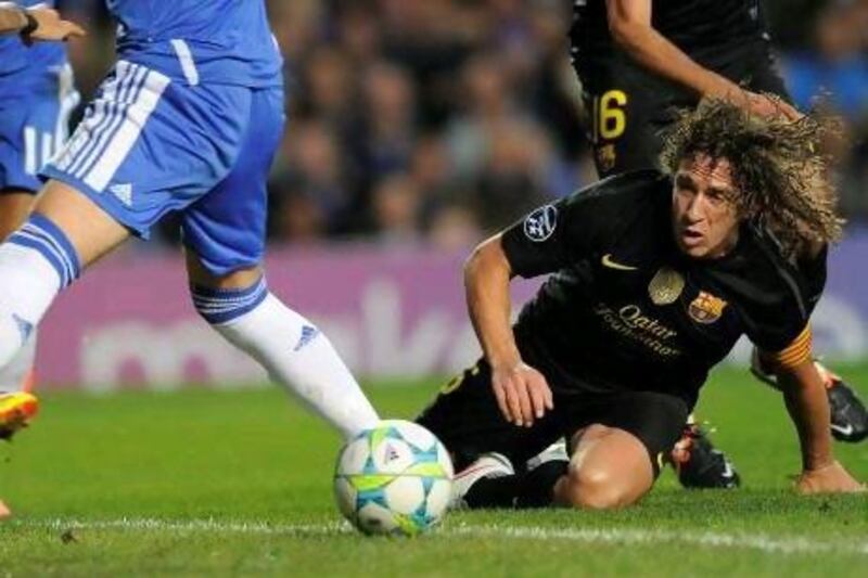 Carles Puyol, the Barcelona captain, tumbles on the soggy pitch at Stamford Bridge last night. Lluis Gene / AFP