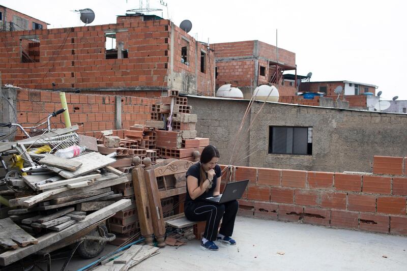 Maria Figueroa attempts to send pictures of her sons’ homework back to their teachers, from the roof of her apartment in the Catia slum of Caracas, Venezuela. AP Photo