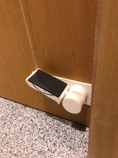 The pivot and lever system consists of only two parts: a rectangular white base can that can be stuck to the base of a door and a cord attached to the door handle.