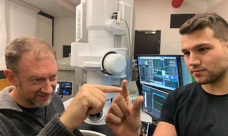 Monash University Professor Andy Tomkins, left, with Royal Melbourne Institute of Technology PhD student Alan Salek study a ureilite meteor sample at an RMIT facility in Melbourne, Australia. Photo: RMIT University