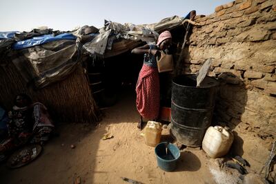 A Sudanese woman who fled the violence in the Darfur region takes water from a barrel in the yard of a Chadian family's house where she is taking refuge, in Koufroun, Chad. Reuters