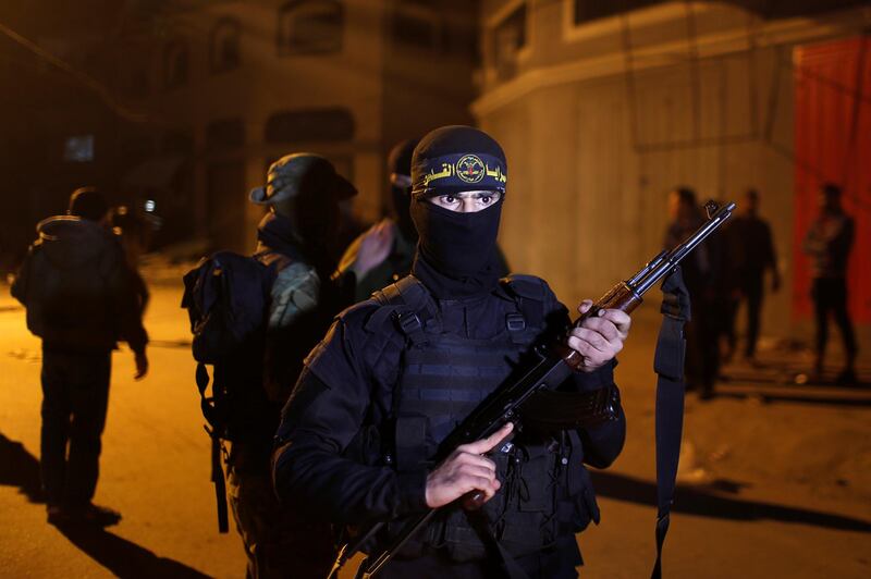 A Palestinian Islamic Jihad militant stands guard at the scene of the Israeli strike. Reuters