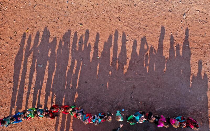 An aerial view taken on October 6, 2020, shows displaced Syrian youths standing in a queue ahead of classes, after tents were transformed to classrooms, at a camp for the internally displaced in the town Maarrat Misrin in Syria’s northwestern Idlib province. (Photo by Omar HAJ KADOUR / AFP)