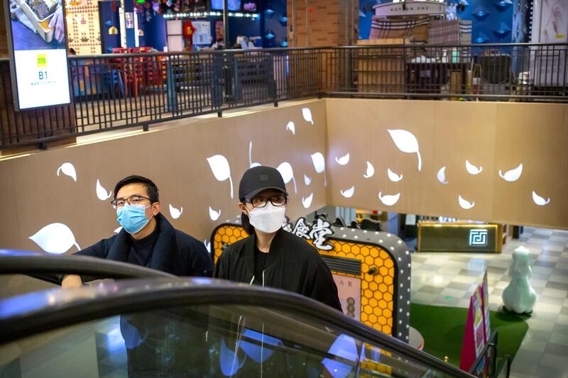 A couple wear face masks as they ride an escalator at a shopping mall in Beijing. AP Photo