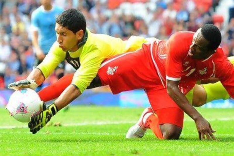 The UAE's Ahmed Khalil, right, gets into a tangle with Uruguay goalkeeper Martin Campana during their Olympic tie at Old Trafford. Andrew Yates / AFP