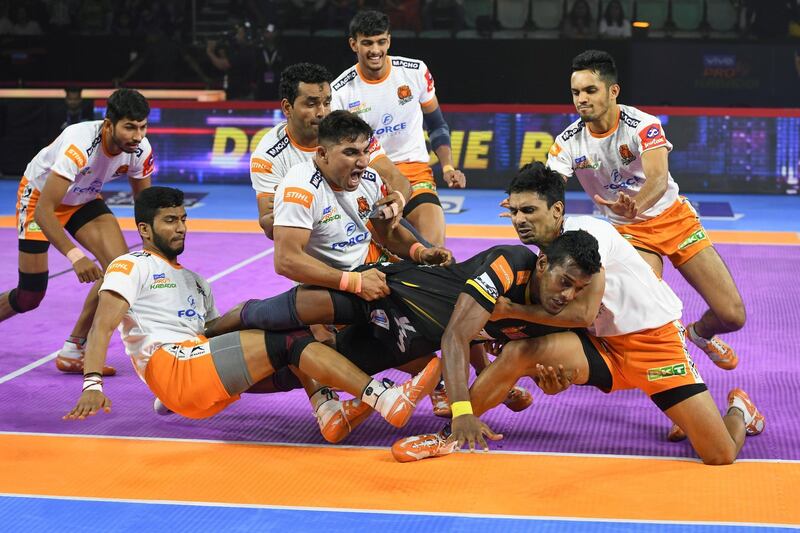 In this photograph taken on August 30, 2019, players of Puneri Paltan hold onto India's Siddharth Desai (C), raider of the Telugu Titans, during the match between Telugu Titans and Puneri Paltan in the Pro Kabaddi League at Thyagaraj Sports Complex in New Delhi. The ancient sport of kabaddi has undergone a glitzy makeover through the Pro Kabaddi League (PKL), creating a new group of sports stars in a country traditionally obsessed with cricket. - To go with 'KABADDI-IND-INDIA,FOCUS' by Faisal KAMAL
 / AFP / Sajjad  HUSSAIN                             / To go with 'KABADDI-IND-INDIA,FOCUS' by Faisal KAMAL
