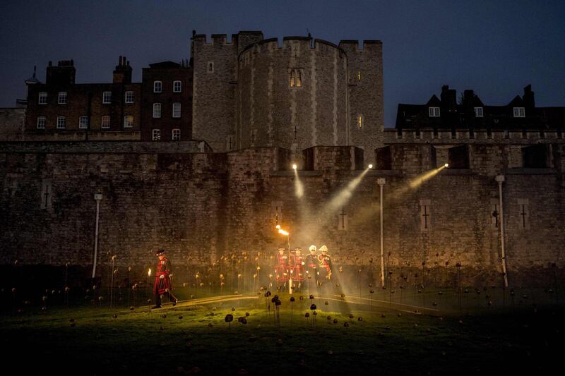 Yeoman Warders, commonly known as 'Beefeaters' light the first of thousands of flames in a lighting ceremony in the dry moat of the Tower of London. AFP