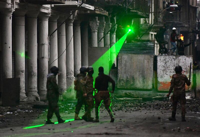 epa08040038 Anti-government protesters behind a barricade in the Al Rasheed street use laser pointers to dazzle Iraqi anti-riot police forces during clashes in central Baghdad, Iraq, 02 December 2019. Protests continue in Baghdad and southern Iraqi cities with rising casualties, while protesters are calling for the resignation of all senior officials in the country after Prime Minister Adel Abdul Mahdi announced to step down.  EPA/MURTAJA LATEEF