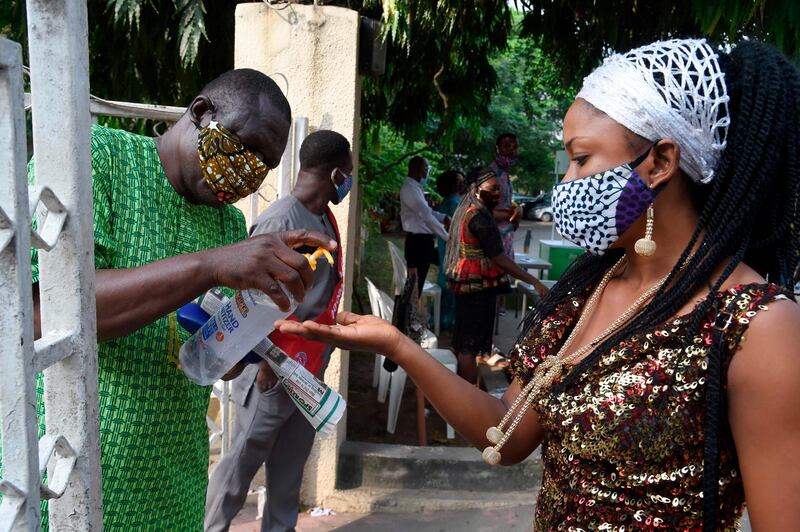 A woman wearing face mask sanitise her hands outside church following the reopening of Churches and lifting of restrictions on religious gatherings by the government as precaution to check the spread of COVID-19 Coronavirus at the Holy Cross Cathedral in Lagos, on August 9, 2020.  Nigerian government has lifted the ban on religious gathering across the country as measure to check the spread of the novel COVID-19 pandemic, but with conditions that worshippers adhere strictly to precautionary measures to curtail the spread of the virus. / AFP / PIUS UTOMI EKPEI
