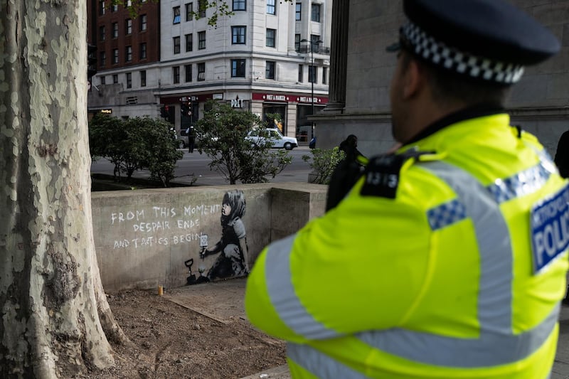 A police officer walks past the street art which is believed to be by Banksy. Getty Images