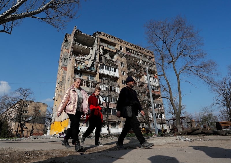 Local residents walk past a damaged apartment building in Mariupol. Reuters