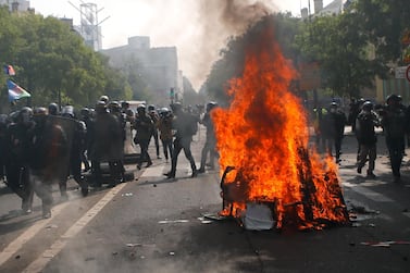 Police officers pass by burning garbage as they confront demonstrators during a May Day rally in Paris, Wednesday, May 1, 2019. Brief scuffles between police and protesters have broken out in Paris as thousands of people gather for May Day rallies under tight security measures. Police used tear gas to control the crowd gathering near Paris' Montparnasse train station. (AP Photo/Francois Mori)