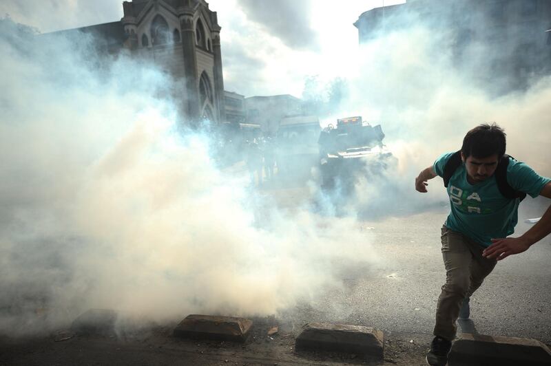 A protester runs for cover during the fourth day of the indefinite strike of education professionals in Santiago, Chile. EPA