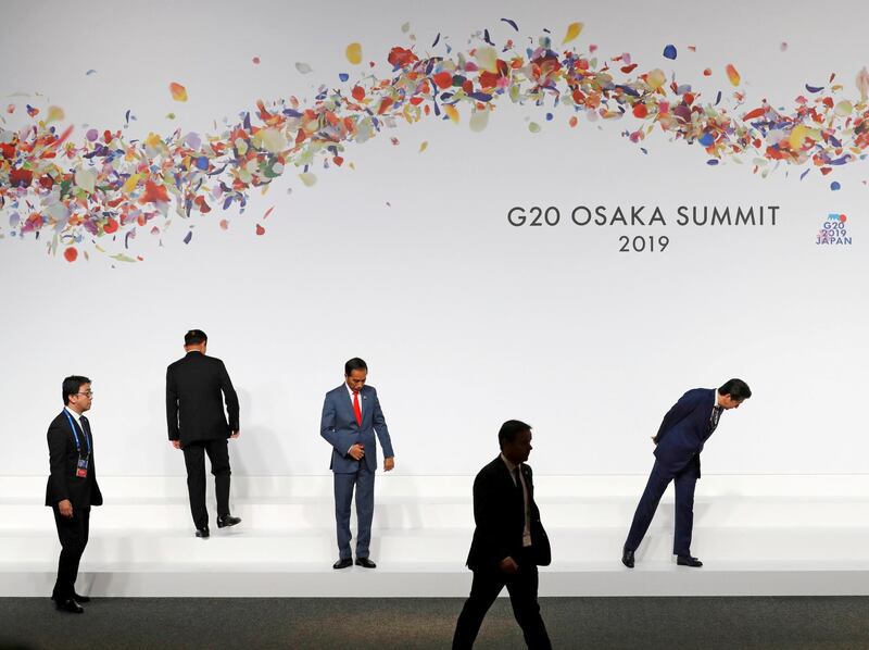 Japanese Prime Minister Shinzo Abe (R) and Indonesian President Joko Widodo (C) check their positions as they prepare for family photo session at the G20 leaders summit in Osaka, Japan. Reuters