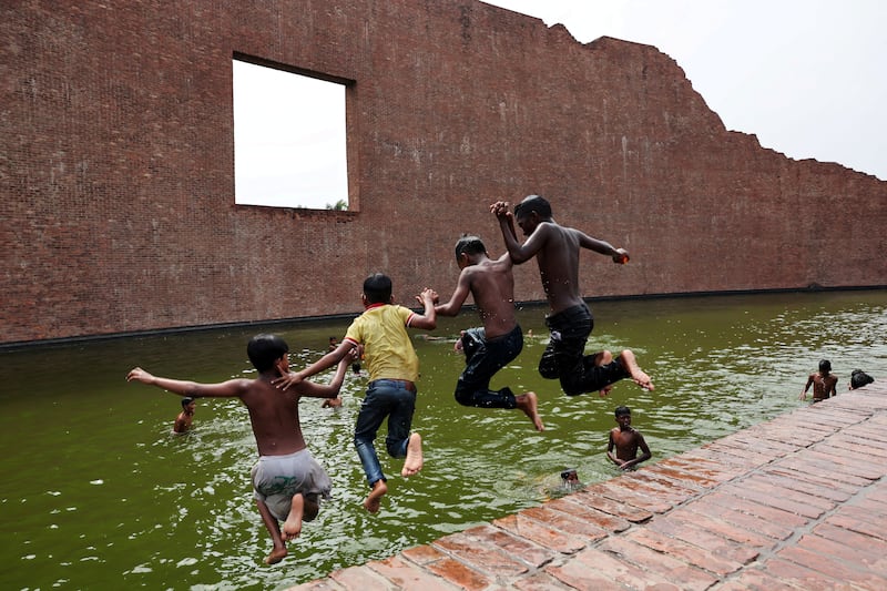 Children jump into a body of water at the Martyred Intellectuals Memorial in Dhaka as they seek respite from the heat. Reuters