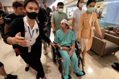 An Australian passenger, centre, who was injured on a flight that was battered by severe turbulence, talks to reporters at Samitivej Srinakarin Hospital in Bangkok. AP