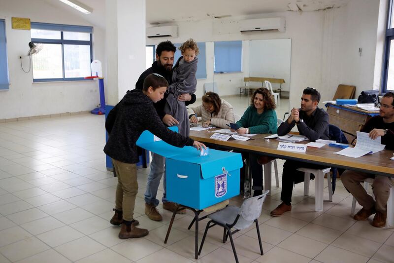 A boy puts his father's ballot in the box. Reuters