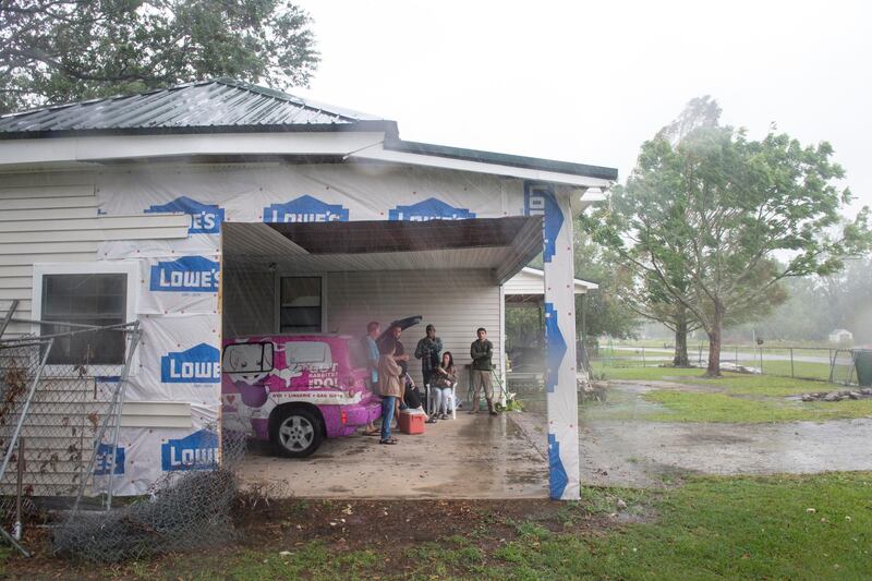 The Lafleur family of Bell City gathers in their garage near where a wall was destroyed by Hurricane Laura several weeks ago, as they watch the arrival of Hurricane Delta.  AP