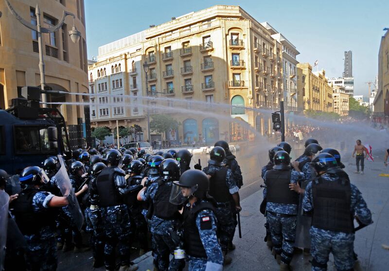 Lebanese police fire water canon during clashes with demonstrators near the parliament in Beirut. Hundreds of Lebanese marched to mark a year since a cataclysmic explosion ravaged the capital.