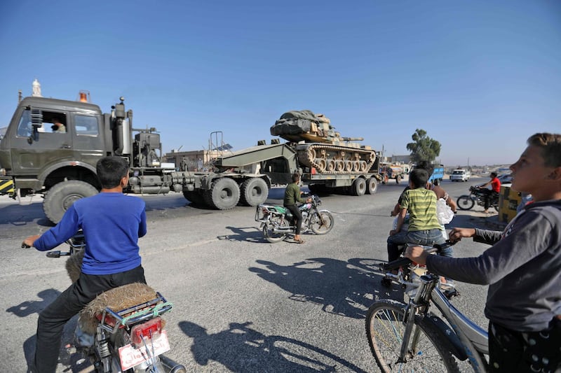 Inhabitants of Maaret Al Numan in Syria's northern province of Idlib watch a convoy of Turkish military vehicles reportedly headed to assist rebels against regime forces.  AFP