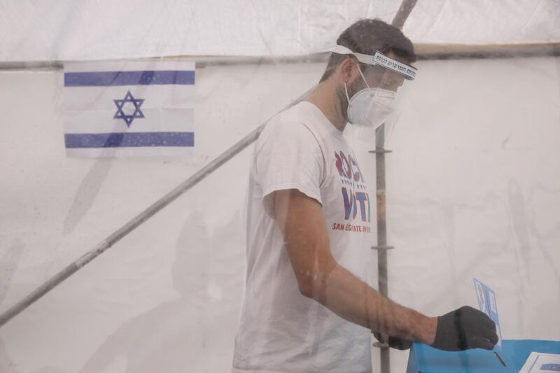 A voter wearing casts his ballot inside a special temporary polling station tent, set up for people quarantined for potential exposure to coronavirus, in Tel Aviv. Bloomberg