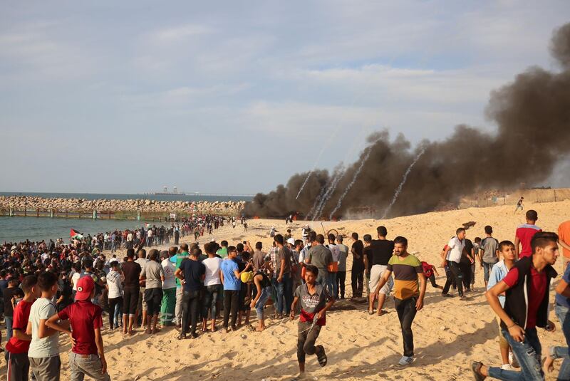 Palestinian protesters run away from tear gas fire on the beach near the maritime border with Israel, in the northern Gaza Strip. AFP