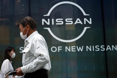 People walk by new logo of Nissan seen at the automaker's showroom in Tokyo. The Japanese automaker's sales crashed amid the coronavirus pandemic and it has struggled to recover from the loss of its former star executive Carlos Ghosn. AP