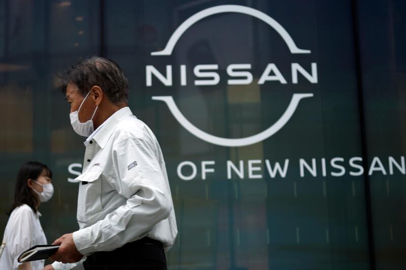 People walk by new logo of Nissan seen at the automaker's showroom in Tokyo Tuesday, July 28, 2020. Nissan reported a 285.6 billion yen ($2.7 billion) loss for April-June, as the Japanese automaker sales crashed amid the coronavirus pandemic and it struggled to recover from the loss of its former star executive Carlos Ghosn.(AP Photo/Eugene Hoshiko)