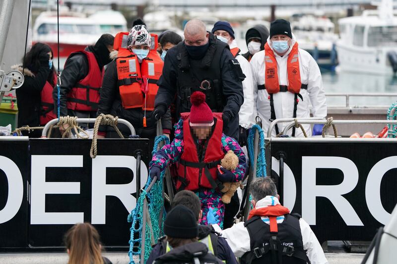 A child clutching a teddy steps ashore in Dover, Kent, southern England, accompanied by Border Force officers after being rescued from a small boat trying to cross the English Channel. PA