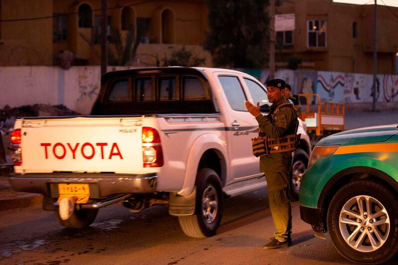 A policeman motions to vehicles passing through a security checkpoint enforcing a curfew due to the COVID-19 coronavirus pandemic in Iraq's southern city of Basra during the Muslim holy fasting month of Ramadan on April 30, 2020.  AFP