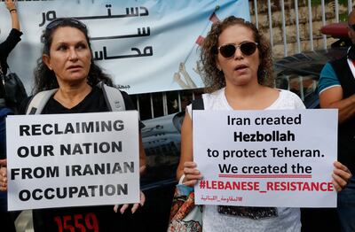 Supporters of Lebanese opposition groups hold placards against Iran and Hezbollah, during a sit-in outside the justice palace to show their solidarity with Judge Tarek Bitar, who is investigating last year's deadly seaport blast, in Beirut, Lebanon, October 19. AP