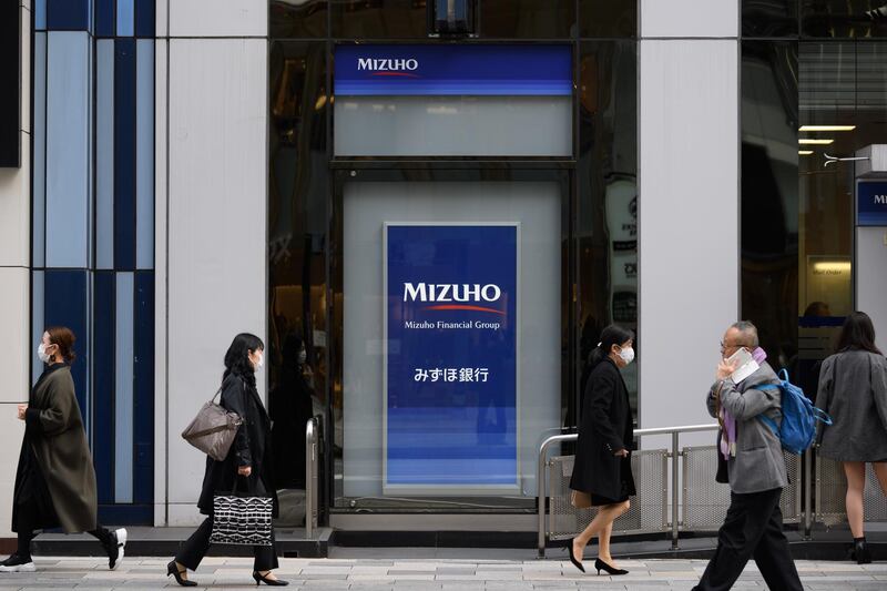 Pedestrians walk past a branch of Mizuho Bank Ltd. in Tokyo, Japan, on Monday, Nov. 9, 2020. Japanese banks expect business opportunities from digitalization, thanks to Prime Minister's Yoshihide Suga's pledge to overhaul outdated paper-based processes. Photographer: Akio Kon/Bloomberg 