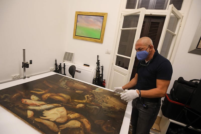 Maamary examines a 17th-century painting by Italian painter Elena Recco, damaged in the Beirut port blast.