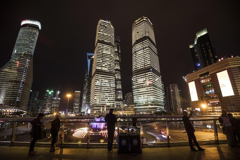 Pedestrians stand on a footbridge in front of commercial buildings illuminated at night in the Lujiazui Financial District in Shanghai, China, on Friday, Oct. 13, 2017. A number of economic indicators show "stabilized and stronger growth" and the momentum of a 6.9 percent expansion in the first six months of 2017 "may continue in the second half," People’s Bank of China Governor Zhou Xiaochuan said. Photographer: Qilai Shen/Bloomberg