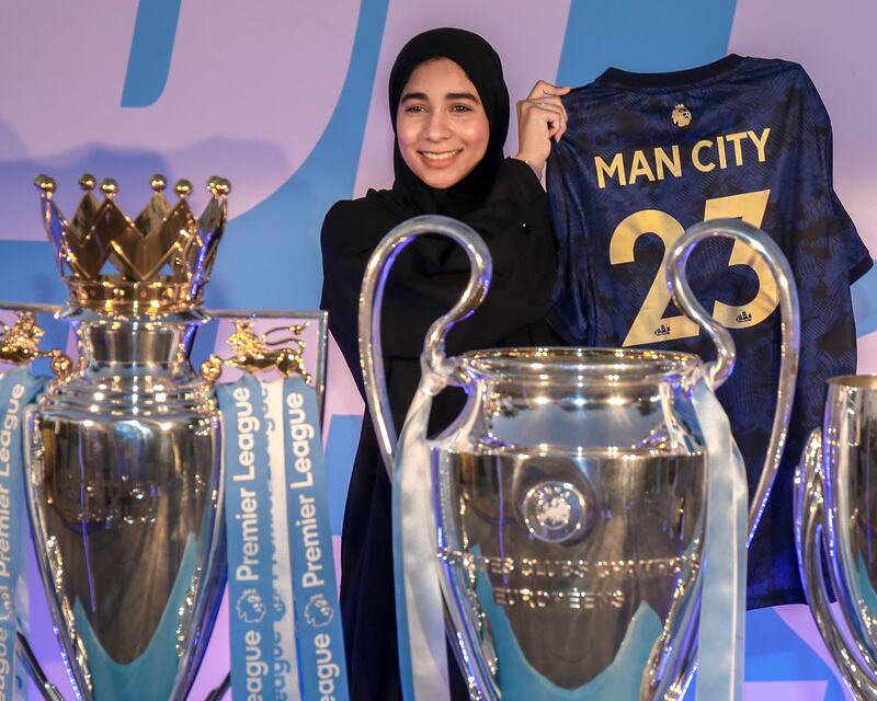 A Manchester City fan poses with the club's trophies