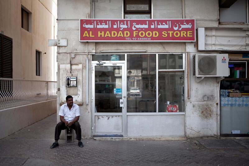 Abu Dhabi, United Arab Emirates, January 10, 2013: 
A man sits by the Al Hadad Food Store, a recently closed convenience store on Thursday, Jan. 10, 2013, in the city block between Airport and Muroor, and Delma and Mohamed Bin Khalifa streets in Abu Dhabi. 
Silvia Razgova/The National

