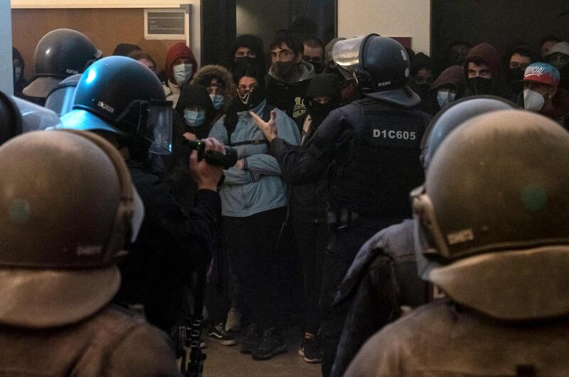 Catalan regional police talk to a group of people attempting to stop the arrest of Pablo Hasel at the University of Lleida. AFP