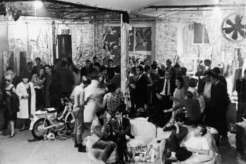 Then: pop artist Andy Warhol's studio The Factory in New York in August 1965. Among those pictured are American photographer Stephen Shore (sitting on couch in foreground, in sunglasses) and filmmaker Shirley Clarke (also on couch, looking through camera). Warhol is also visible at centre rear (at the seam between the cow-print and mylar wallpapers). Fred W McDarrah / Getty Images