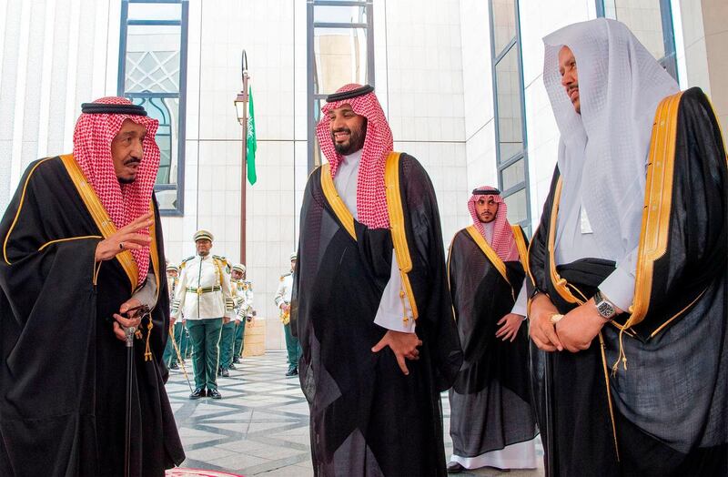 King Salman talks to the secretary general of the Shura Council, a top advisory body, Abdullah Al-Sheikh, right, as Prince Mohammed bin Salman looks on, at the council. Saudi Royal Court / AFP