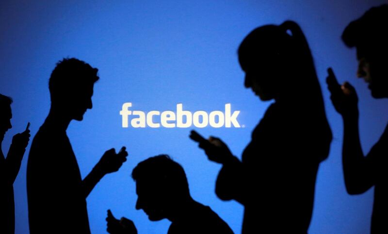 FILE PHOTO:  People are silhouetted as they pose with mobile devices in front of a screen projected with a Facebook logo, in this picture illustration October 29, 2014. REUTERS/Dado Ruvic/Illustration/File photo