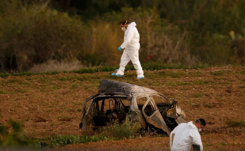 Forensic experts walk the field where a bomb blew up a car and killed investigative journalist Daphne Caruana Galizia in Bidnija, Malta, on October 16, 2017.