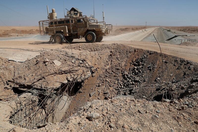 A US armoured vehicle passes next to a destroyed bridge on a road that links to Raqqa city, northeast Syria, on Wednesday, July 26, 2017. AP  / Hussein Malla