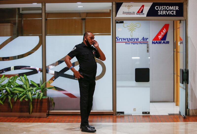 An aviation security officer uses a phone as he stands outside Sriwijaya Air customer service at Soekarno-Hatta International Airport. Reuters