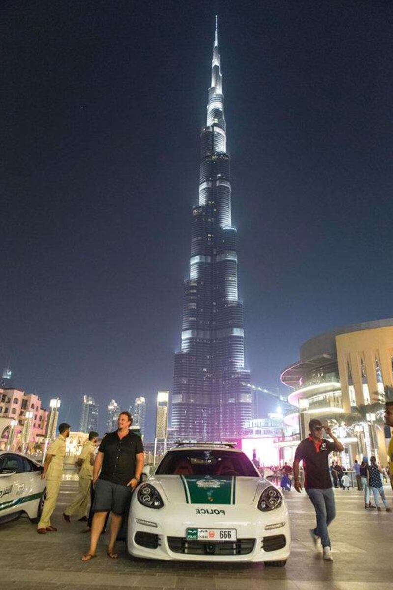 People have their photo taken with the Porche Panamera S E-Hybrid with Burj Khalifa as the backdrop.
