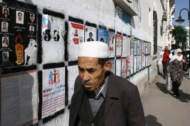 Tunisians pass election wall posters in Tunis last October. Ahmed Bouazzi, of the Progressive Democratic Party, says one mistake the party made was to heed the advice of campaign consultants to plaster walls with posters of party leaders, recalling Ben Ali’s once ubiquitous portraits.