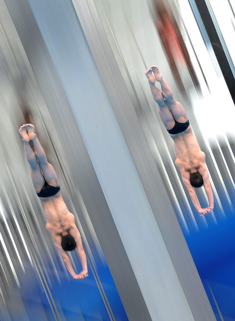 North Korea's Ri Hyon Ju and Hyon Il Myong compete in the men's 10-metre synchronised platform preliminary round diving event in the FINA World Championships at the outdoor diving pool of the Oriental Sports Centre in Shanghai on July 17, 2011. TOPSHOTS    AFP PHOTO / MARK RALSTON
 *** Local Caption ***  437110-01-08.jpg