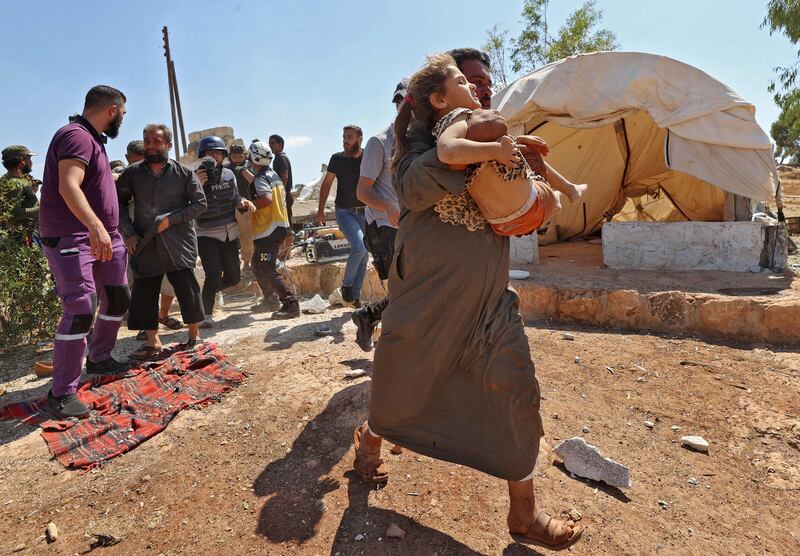 A man carries a girl who was injured during shelling at a makeshift camp for displaced Syrians near the town of Kafraya, in the north of Syria's rebel-held Idlib province, on Tuesday.  AFP